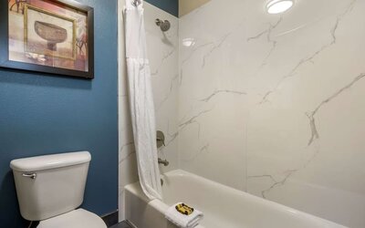 Bathroom with a bathtub, shower, toilet, and marble-look wall surround at Best Western Plus Mountain View Auburn Inn.