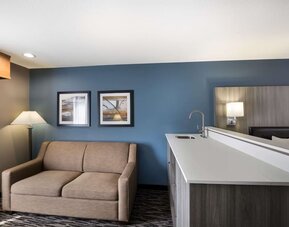 Suite seating area with a sofa, counter, sink, and lamp at Best Western Plus Mountain View Auburn Inn.