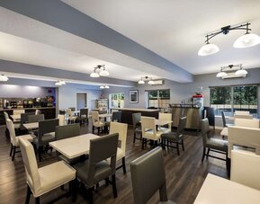 Breakfast area with tables, chairs, buffet, coffee station, and large windows at Best Western Plus Mountain View Auburn Inn.
