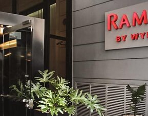 Hotel entrance with glass doors, illuminated Ramada by Wyndham signage and potted plants at Ramada by Wyndham Buenos Aires Centro.