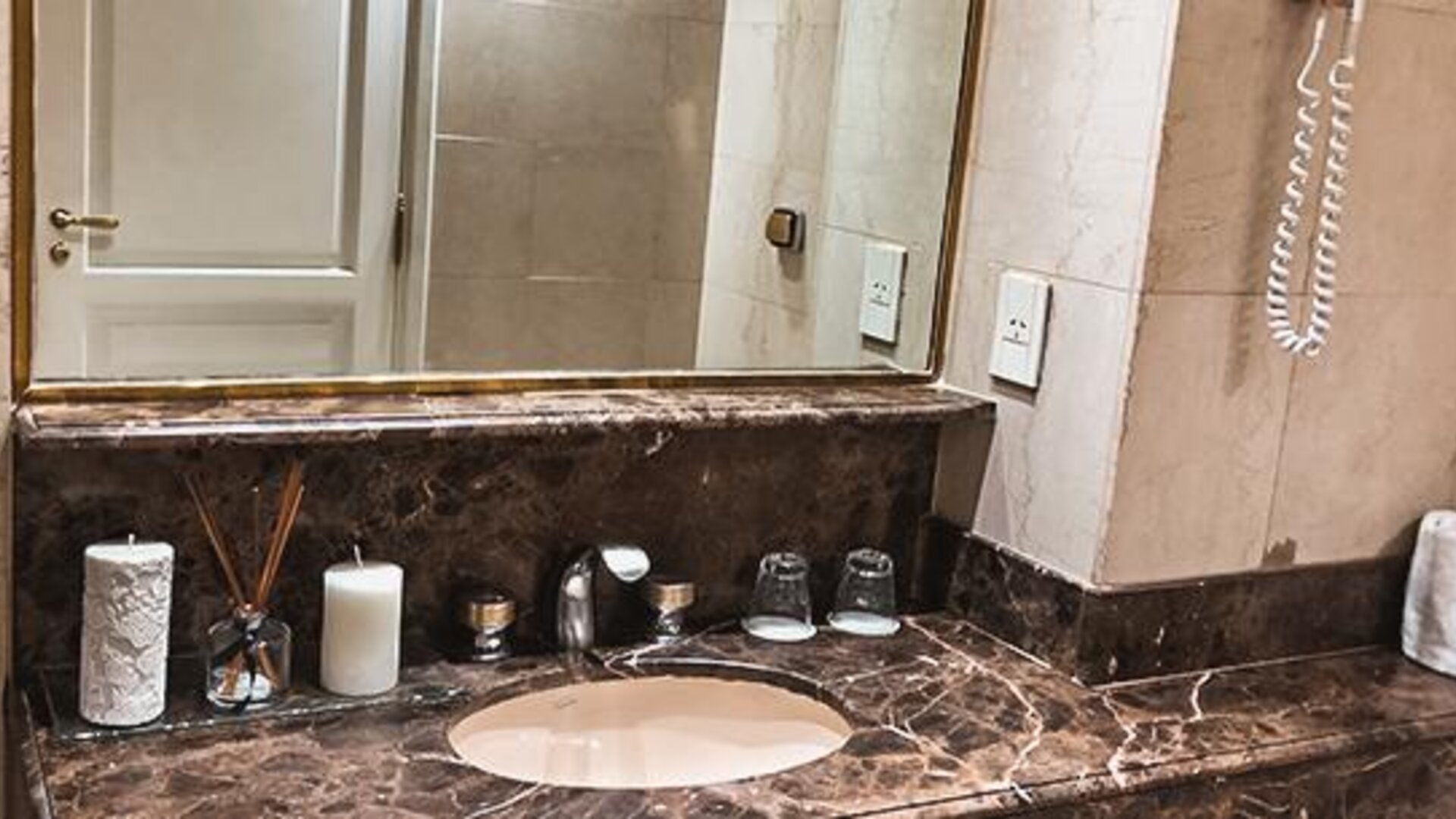 Bathroom vanity with marble countertop, oval sink, large mirror and toiletries at Ramada by Wyndham Buenos Aires Centro.