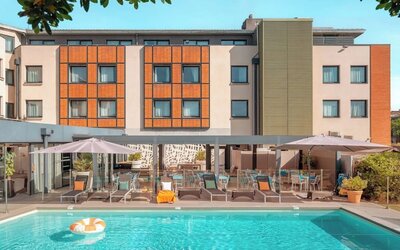 Outdoor swimming pool surrounded by sun loungers, umbrellas, patio seating, and the hotel building at Holiday Inn Toulouse Airport.