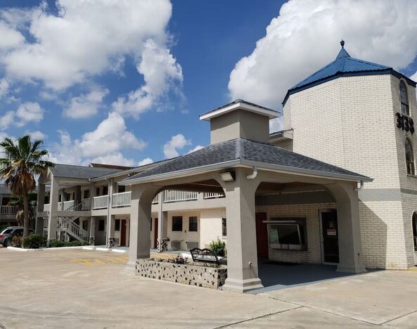Exterior side view of Summit Inn Near Houston Medical Center-NRG Park showing the hotel building, covered walkway, landscaping, and accessible parking.