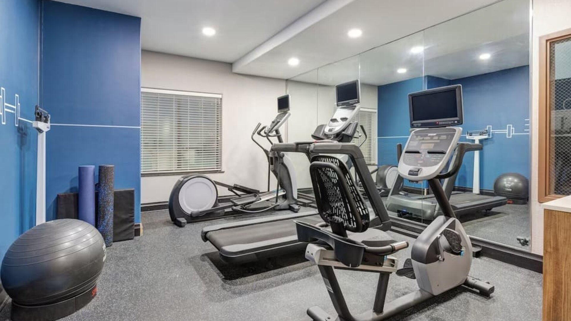 Hotel fitness center with treadmills, elliptical machines, stationary bike, exercise balls, and mirrored walls at Holiday Inn Express & Suites Granbury.