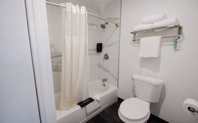 Guest room with two beds, white bedding, green accent wall, bedside lamps, and a window with natural light at Western Inn.
