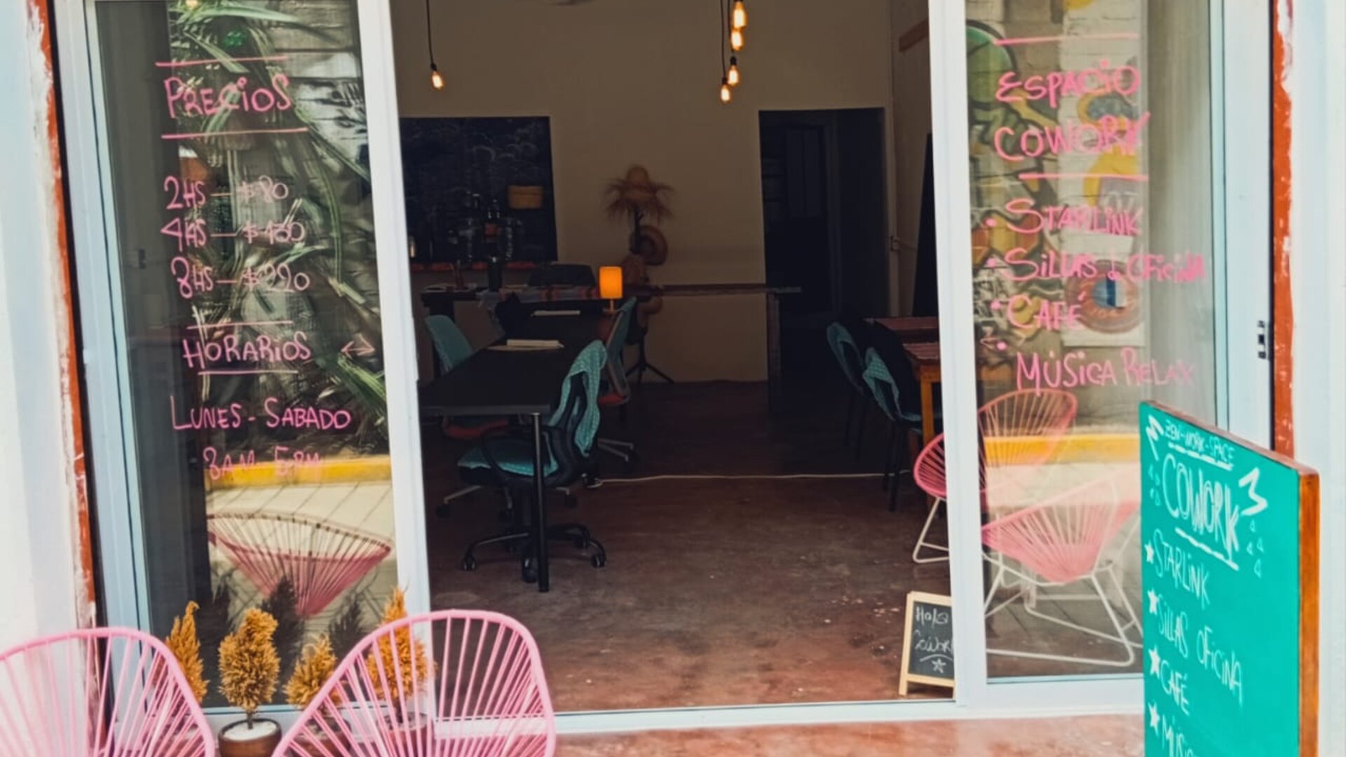 Entrance of the CoWork Zipolite cafe' with pink acapulco chairs at the entrance and a door to make the space more comfortable and sound-proof.