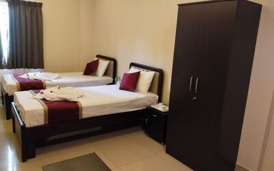 Twin bed hotel room featuring white bedding, burgundy accents, decorative towel arrangements, dark wooden furniture, a spacious wardrobe, and tiled flooring.