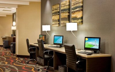 Business center featuring multiple computer workstations, office chairs, desk lamps, and wall art at Best Western Plus BWI Airport Arundel Mills.