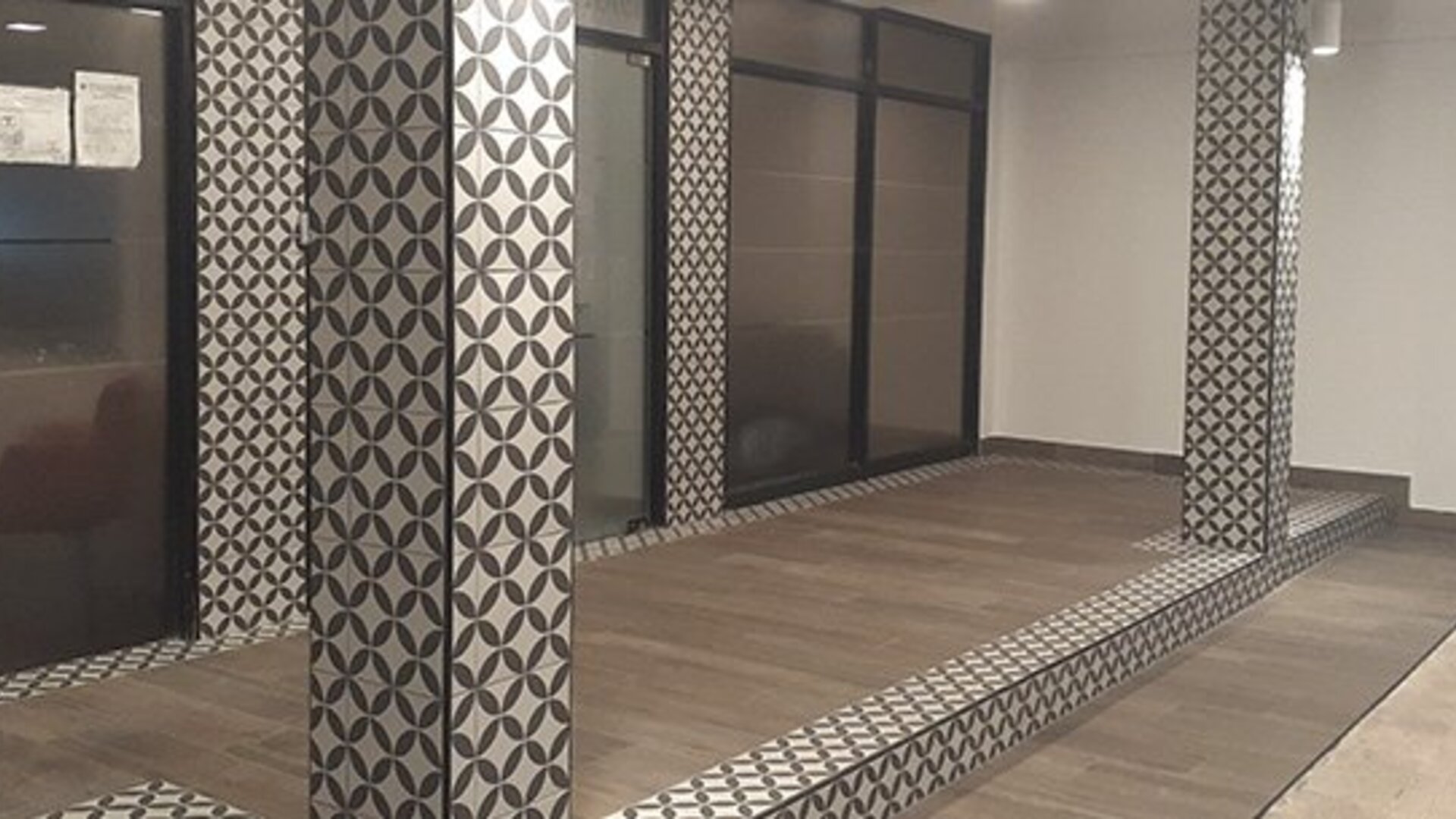 A modern hotel interior with patterned columns, glass partitions, tiled flooring and a raised platform at Residencial & Hotel Palazzo.
