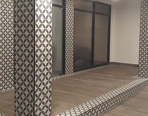 A modern hotel interior with patterned columns, glass partitions, tiled flooring and a raised platform at Residencial & Hotel Palazzo.