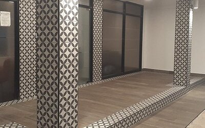 A modern hotel interior with patterned columns, glass partitions, tiled flooring and a raised platform at Residencial & Hotel Palazzo.