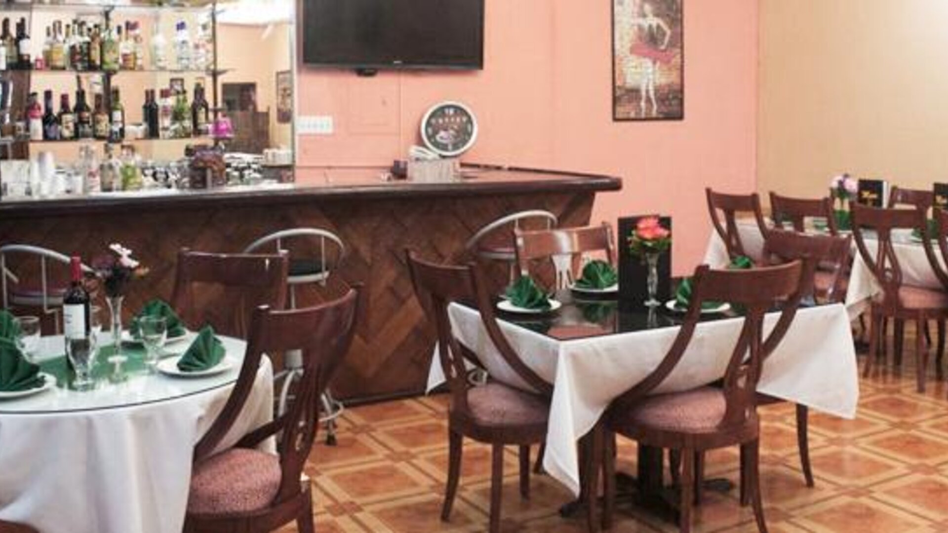 Restaurant with round tables, white tablecloths, wooden chairs and a stocked bar at Caribe Panamá Hotel.