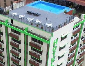 Multi-storey hotel exterior with green trim, rows of balconies and a rooftop swimming pool at Caribe Panamá Hotel.