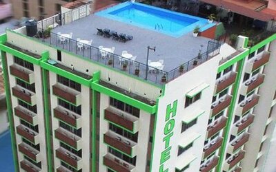 Multi-storey hotel exterior with green trim, rows of balconies and a rooftop swimming pool at Caribe Panamá Hotel.