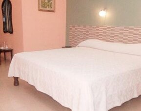 Double bed with white bedding, a geometric headboard and wall-mounted bedside lights at Caribe Panamá Hotel.