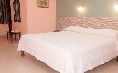 Double bed with white bedding, a geometric headboard and wall-mounted bedside lights at Caribe Panamá Hotel.