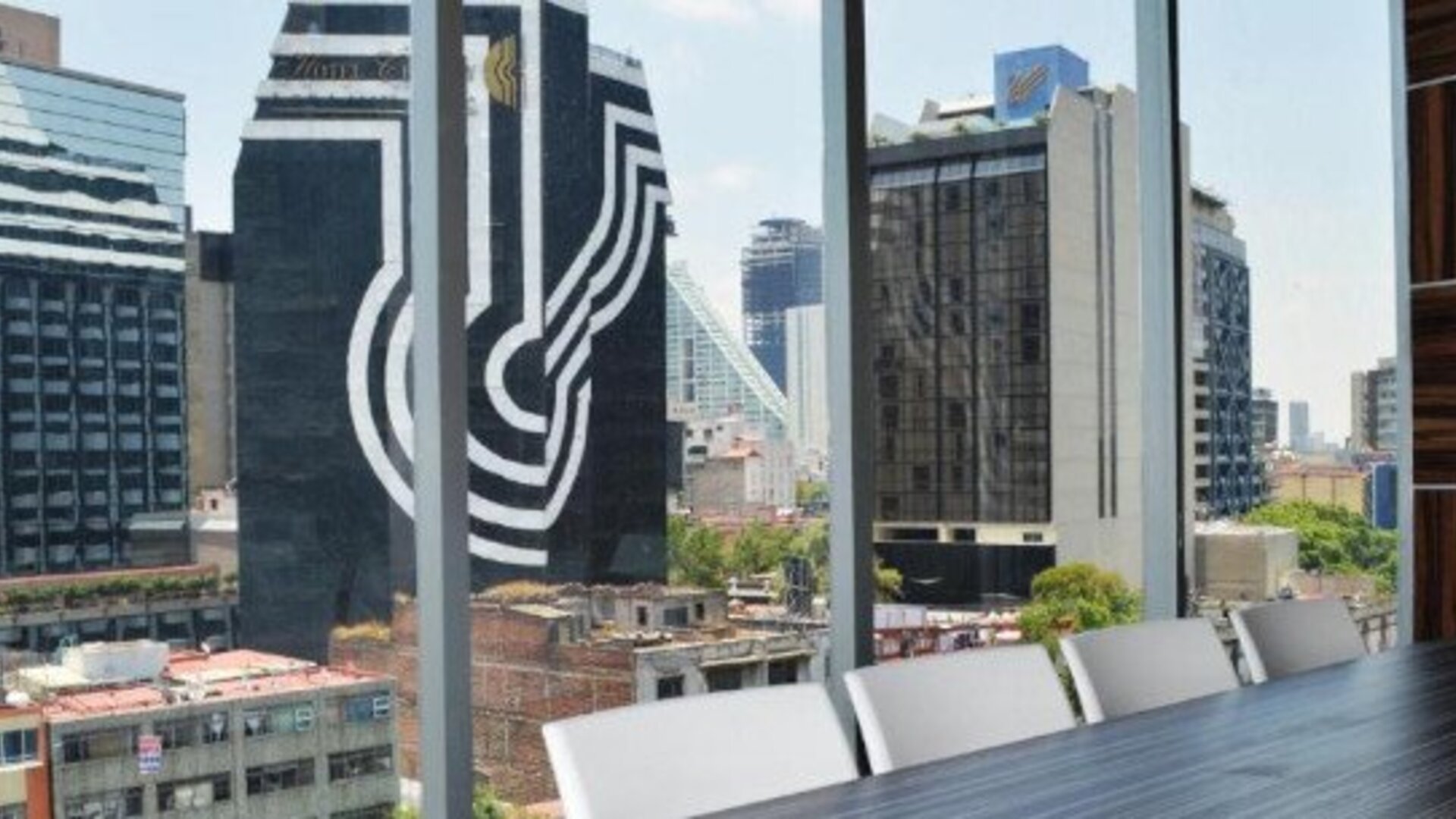 Meeting facility with a long table, white chairs, colourful wall panels and floor-to-ceiling windows at Hotel Block Suites.