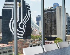 Meeting facility with a long table, white chairs, colourful wall panels and floor-to-ceiling windows at Hotel Block Suites.