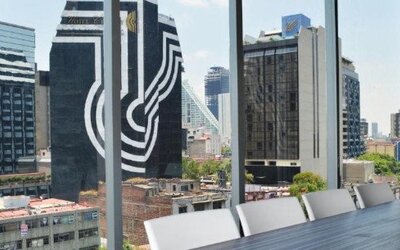 Meeting facility with a long table, white chairs, colourful wall panels and floor-to-ceiling windows at Hotel Block Suites.