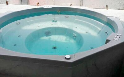 Indoor whirlpool bath with turquoise water, built-in seating and tiled surround at Hotel Block Suites.