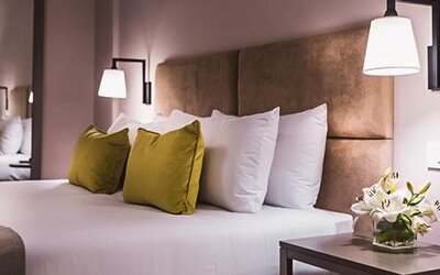 1. Guest room with a king-size bed, white bedding, olive-green accent cushions, upholstered headboard and bedside lighting at Howard Johnson Plaza Buenos Aires.