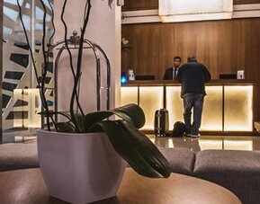 Reception area with a backlit front desk, decorative stone wall, seating and glass entrance at Howard Johnson Plaza Buenos Aires.