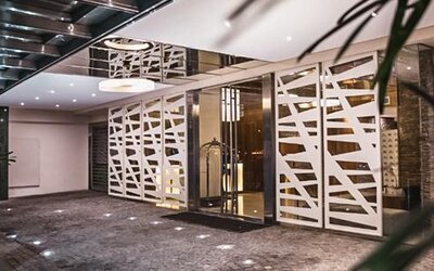 Hotel entrance with glass doors, white geometric screens, dark stone flooring and potted plants at Howard Johnson Plaza Buenos Aires.