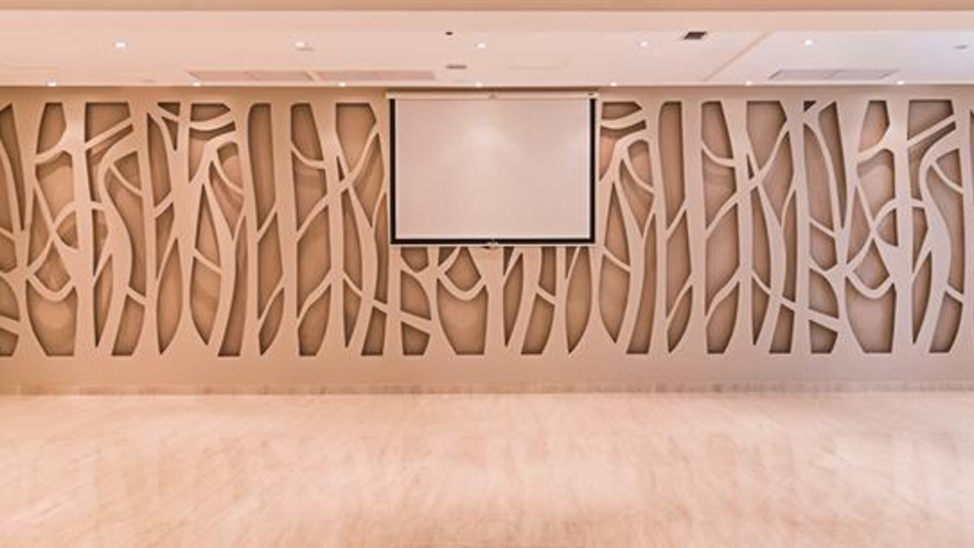 Conference room with decorative geometric wall panels, projection screen and polished flooring at Howard Johnson Plaza Buenos Aires.