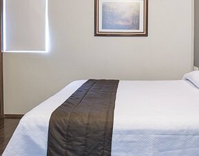 Guest room with a double bed, white bedding, dark wooden headboard and bedside telephone at Hotel Principal.