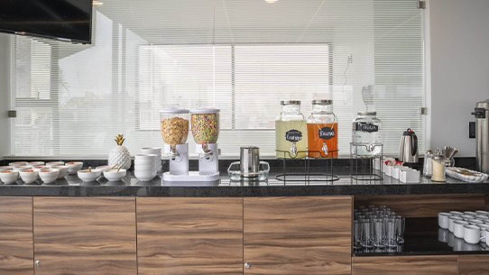 Breakfast beverage station with cereal dispensers, juice dispensers, coffee equipment, cups and glassware at Hotel Principal.