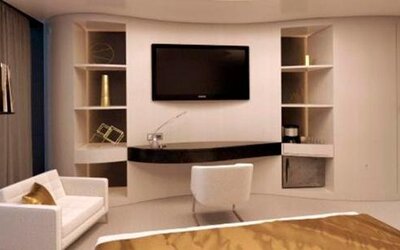 Contemporary guest suite with a wall-mounted television, cream seating, a desk and floor-to-ceiling windows at Hotel Las Américas Golden Tower Panamá.