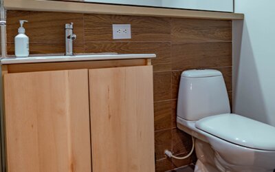 Bathroom with a light wood vanity, white sink, wall-mounted mirror and wood-effect tiled backsplash at UMA Suites Chía.