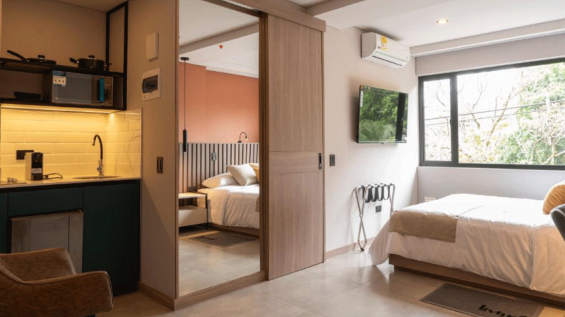 Studio-style guest room with a double bed, kitchenette, mirrored sliding wardrobe, air conditioning, and large windows at Hotel Living 35 Suites.