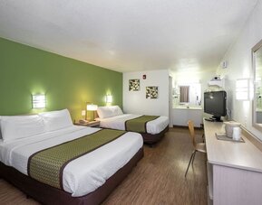 Guest room with two double beds, white bedding, green accent wall, matching bed runners, a television, and a long work desk at American Inn Carlisle.