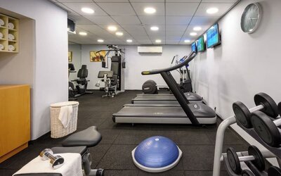 Hotel fitness centre equipped with treadmills, weight machines, dumbbells, an exercise ball, and wall-mounted televisions at Prima Park Hotel.
