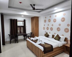 Guest room featuring a double bed with white bedding, red and gold accents, decorative towel arrangements, wooden furniture, a wardrobe, and a small table with two chairs at Hotel Urban Abode.
