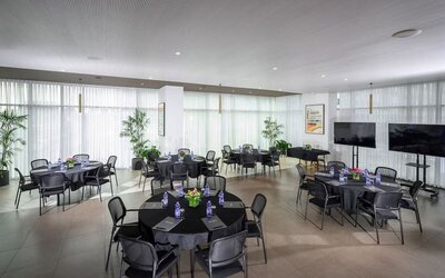 Meeting space with round tables, black tablecloths, chairs and floor-to-ceiling curtains at Prima Link.