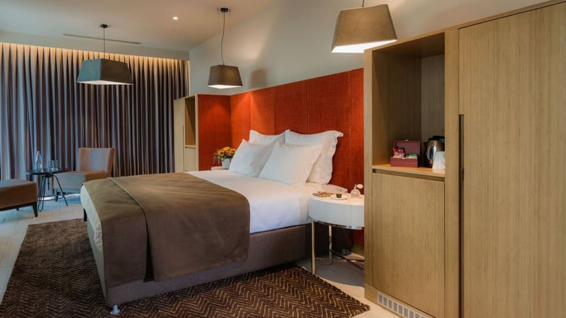 Spacious guest room with a king bed, brown throw, orange headboard and wooden cabinetry at Prima Link.