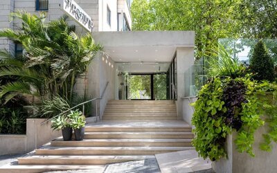 Hotel entrance with wide stone steps, glass doors and landscaped greenery at Prima Galil Tiberias.