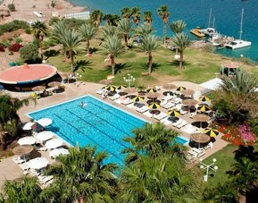 Aerial view of the outdoor swimming pool surrounded by palm trees, sun loungers and landscaped gardens beside the Red Sea at Prima Music Eilat