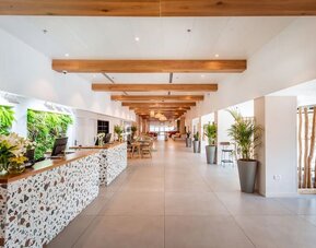 Hotel reception area with a decorative stone-fronted desk, greenery and a long, bright lobby at Prima Music Eilat.