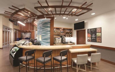 Hotel bar with curved counter, bar stools and beverage display at Hyatt Place Portland Airport at Cascade Station.