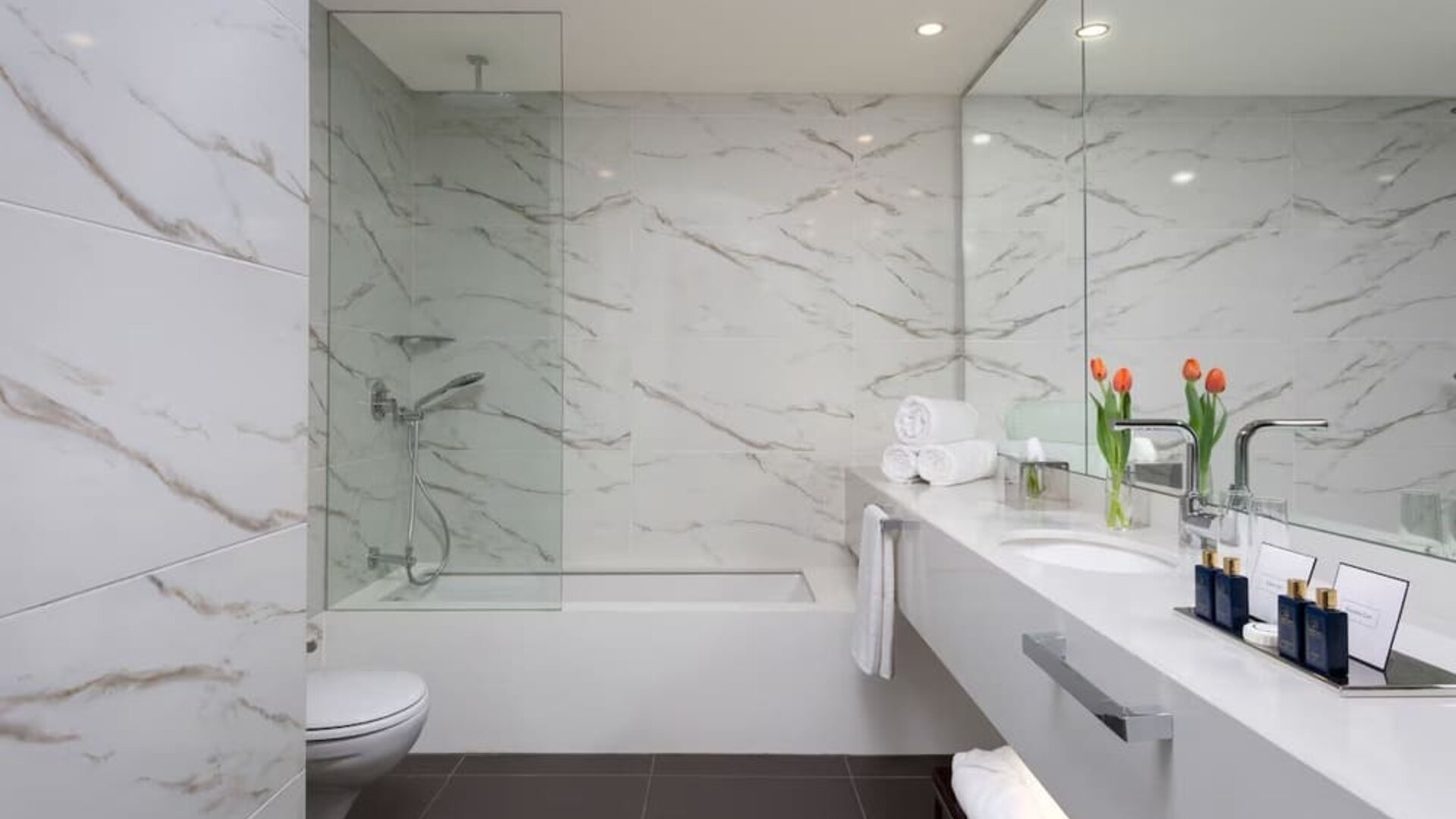 Bathroom with marble-effect walls, bathtub, glass shower screen and double vanity at Lady Stern Hotel.