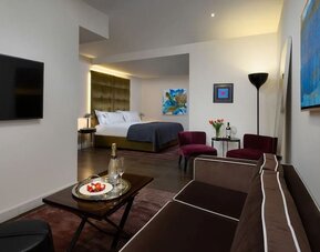 Spacious suite with sofa, coffee table, lounge chairs and separate sleeping area at Lady Stern Hotel.