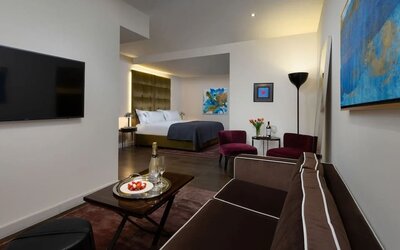 Spacious suite with sofa, coffee table, lounge chairs and separate sleeping area at Lady Stern Hotel.