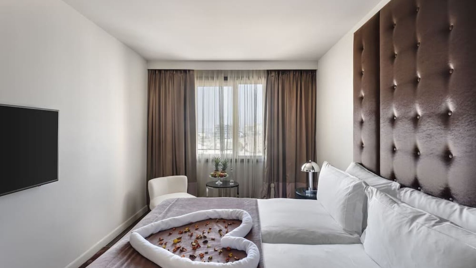 Guest room with king bed, tall upholstered headboard and decorative towel arrangement at Lady Stern Hotel.