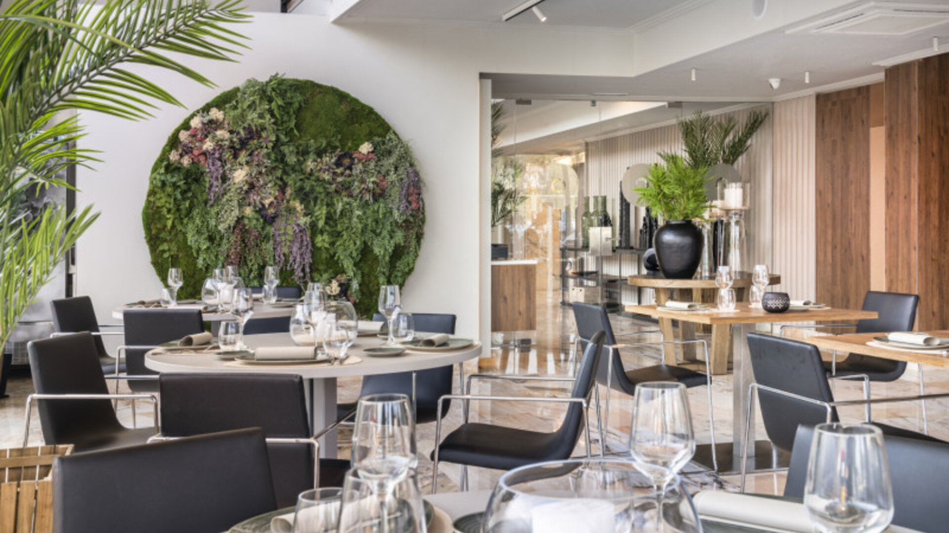 Restaurant dining room with wooden tables, black chairs, place settings and warm illuminated wall panels at Hotel Sallés Ciutat del Prat.