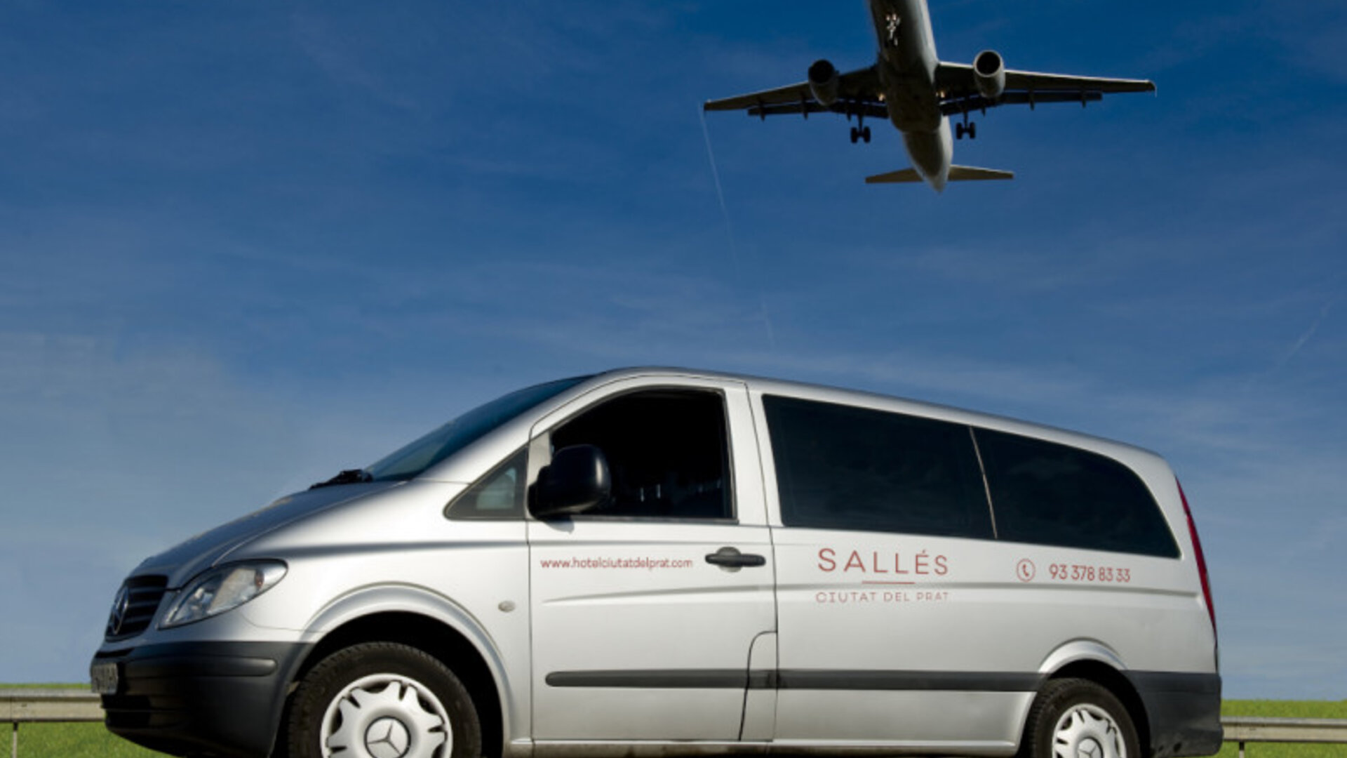 Silver Mercedes passenger van displaying hotel branding beneath a clear blue sky at Hotel Sallés Ciutat del Prat.
