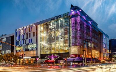 Modern glass-fronted hotel exterior illuminated with purple lighting against the evening sky at Sonesta Hotel Bogotá.