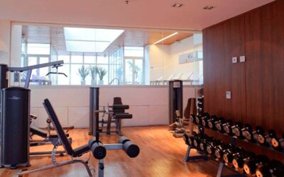 Fitness centre with weight machines, adjustable benches and dumbbell racks beside wooden flooring at Design Suites Buenos Aires.